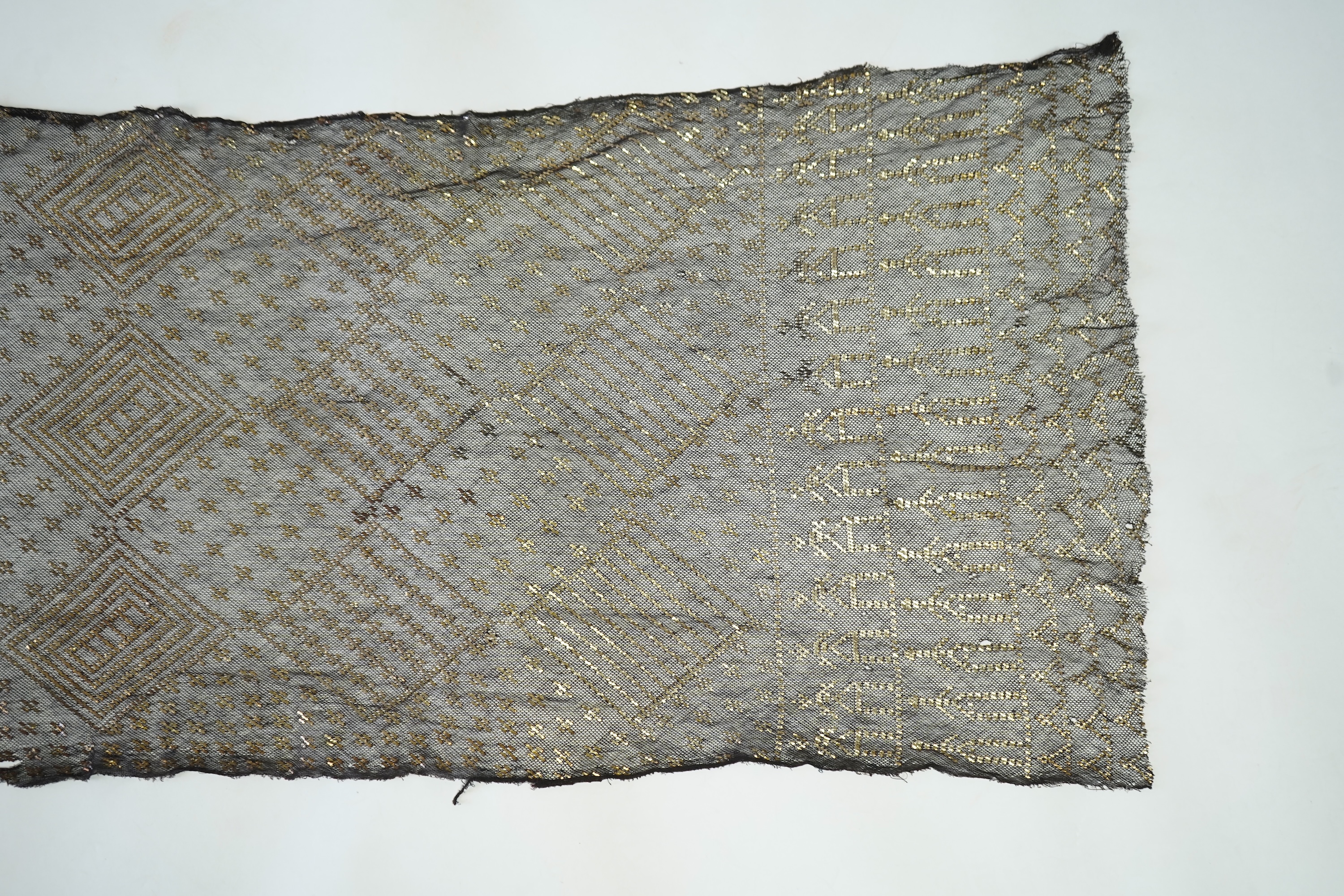 A 1930’s Egyptian decorative metal on black net evening stole. Approximately 218cm long. Condition - the rolled edges are frayed but the colour and design are intact.